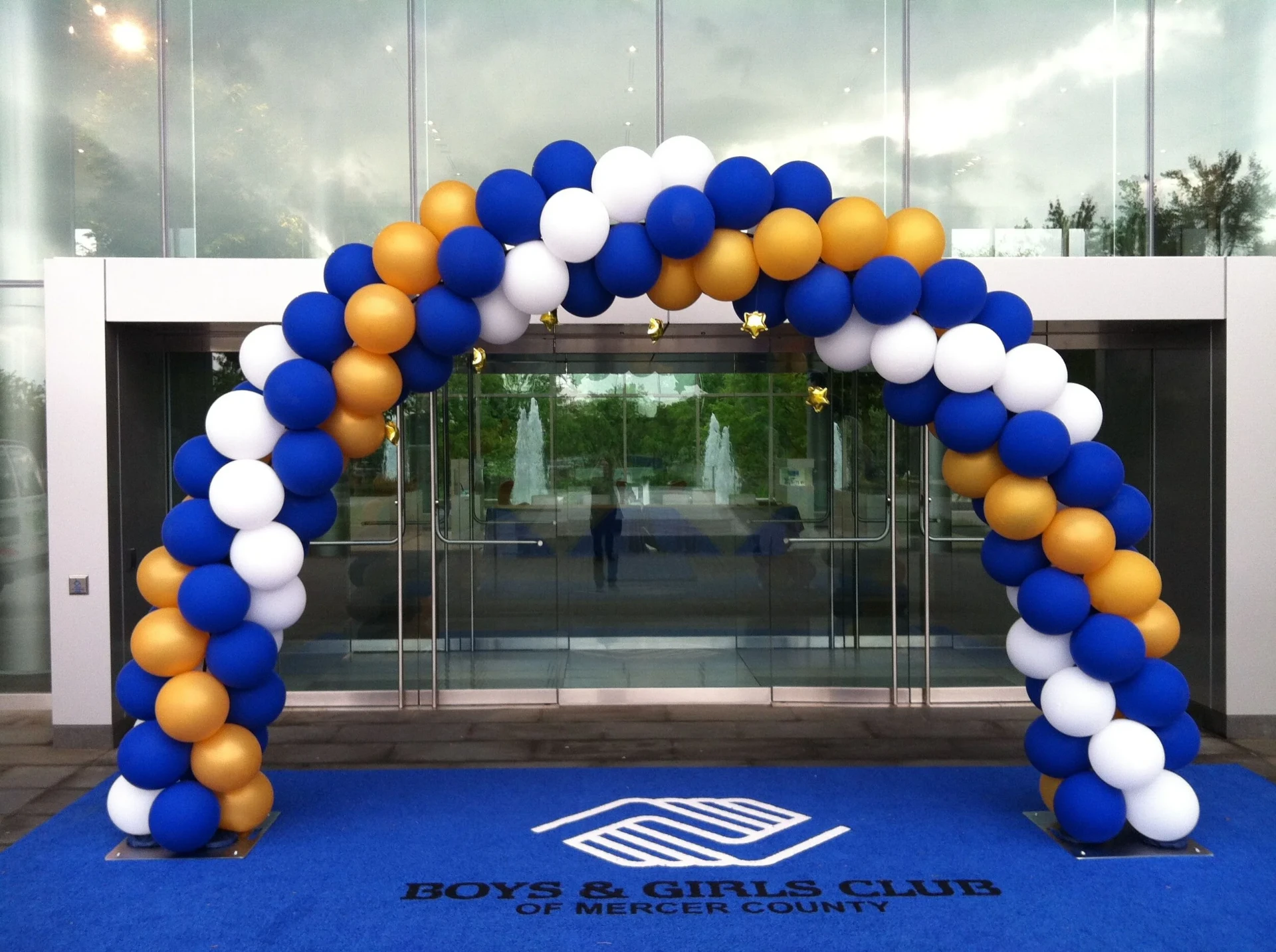 Large blue, white, and gold classic balloon arch over an event entrance