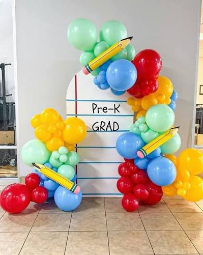 Rainbow organic balloon arch with pencil foils on a Pre-K Grad backdrop