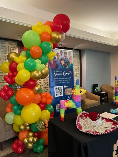 Red, yellow, green, orange, and gold fiesta balloon column with pinata accents