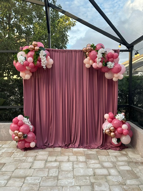 Burgundy drape backdrop with pink, blush, and rose gold balloon accents