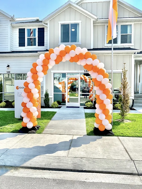 Orange and white classic balloon arch framing a building entrance