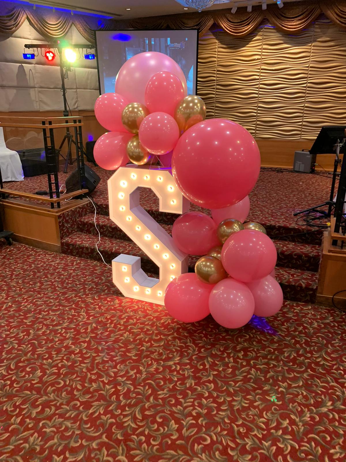 Light-up marquee letter S with pink and gold balloon styling