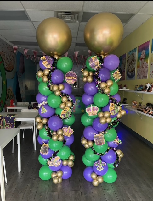 Mardi Gras themed purple, green, and gold balloon columns with masks and crown accents